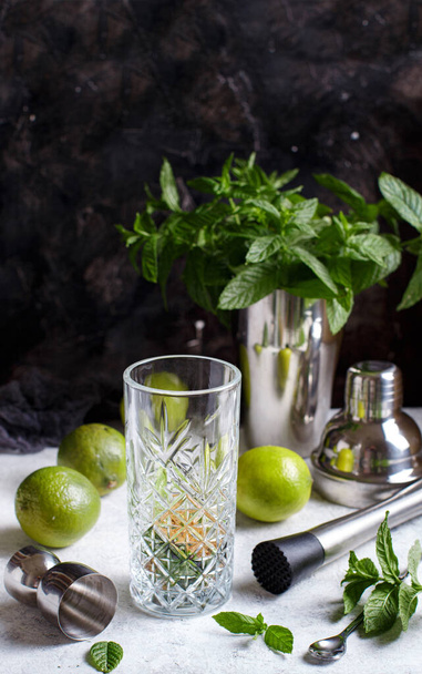 Mojito cocktail fabrication - Menthe, citron vert, glace, grand verre et outils barmen fermer - Photo, image