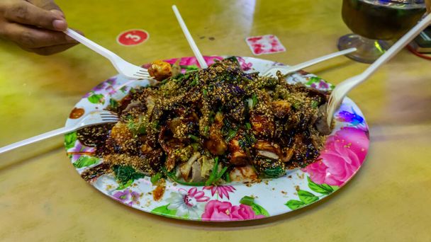 Ihmiset syövät Yong Tau Foo tai Yentafu, kiinalainen keittiö muovihaarukalla pöydällä. Koostuu jauhelihaseoksella tai kalatahnalla täytetystä tofusta. Kuva sisältää melua ja valikoivaa keskittymistä. - Valokuva, kuva