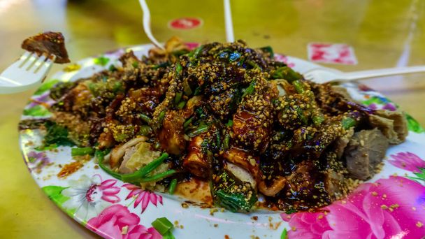 Gente comiendo Yong Tau Foo o Yentafu, una cocina china usando tenedor de plástico sobre una mesa. Consta de tofu relleno con mezcla de carne molida o pasta de pescado. La imagen contiene ruido y enfoque selectivo
. - Foto, Imagen