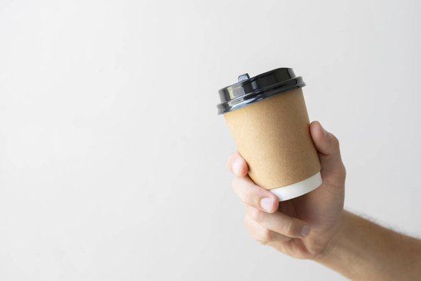男の手を閉じて熱いコーヒーカップを持っているソフトフォーカスと背景の光の上に - 写真・画像