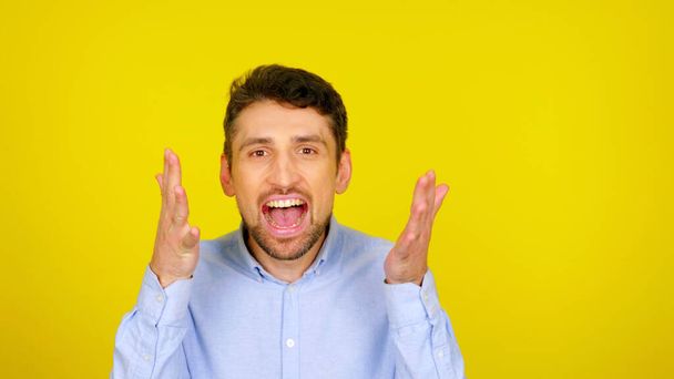 Man with open mouth in a light blue shirt on a yellow background with copyspace - Photo, Image