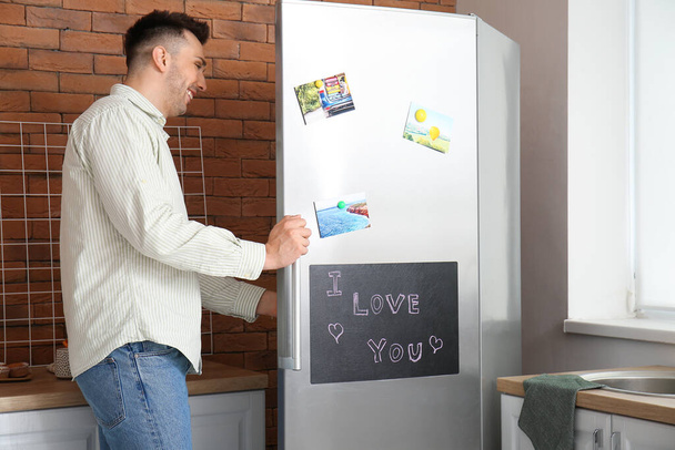 Hombre joven abriendo refrigerador en cocina
 - Foto, imagen