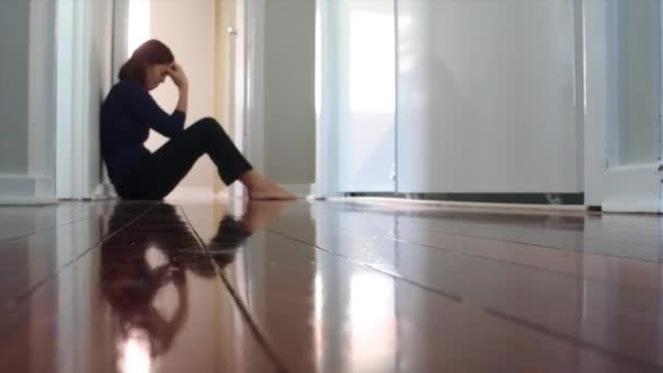Surullinen aikuinen yksinäinen nainen istuu pimeässä kotikäytävällä lattialla. - Materiaali, video