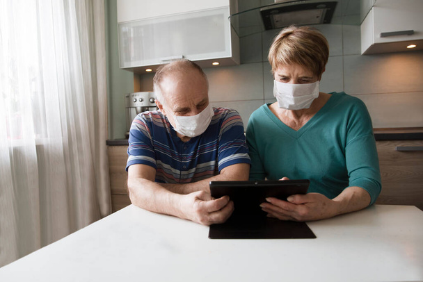 Seniors couple  wearing medical face mask and using tablet at home. quarantine. health concept. Corona Virus. order of products online - Fotografie, Obrázek