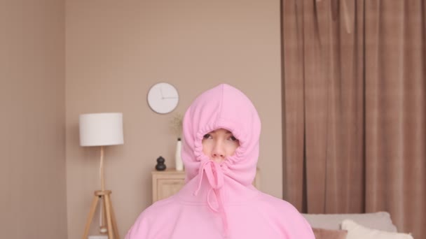 Woman in social isolation at home. Introvert avoids communication, sad in depression. Loneliness and self-isolation. Cozy home decor. Day off and sick leave. Woman in a pink hood. Social distance.  - Footage, Video