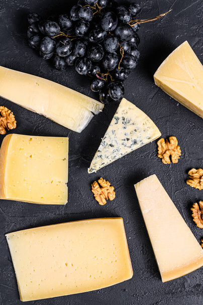 Diferentes tipos de deliciosos queijos com nozes e uvas. Fundo preto. Vista superior. - Foto, Imagem