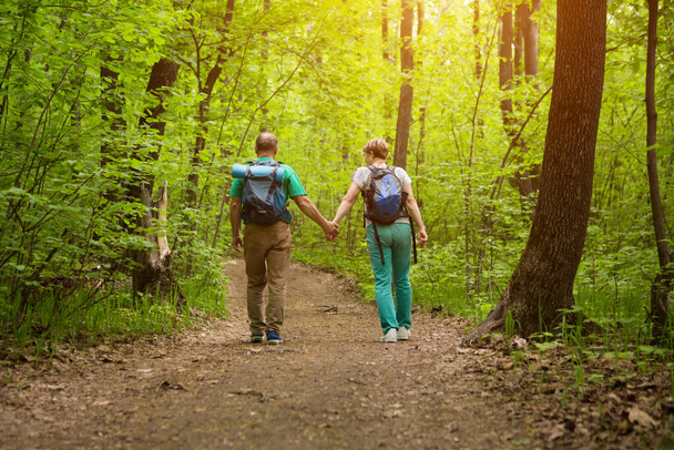 elderly couple with backpack hiking in forest. Senior couple walking in nature. end of a quarantine. Staycations, hyper-local travel,  family outing, getaway, natural environ - 写真・画像