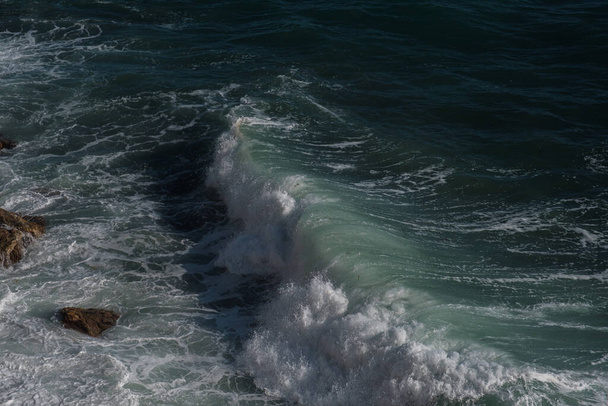 Ωκεανό κύμα φόντο θραύση θάλασσα νερό βραχώδη ακτή ακατέργαστων θαλασσών τυρκουάζ νερό κλίση αφρό. Μεγάλα κύματα στην ανοιχτή θάλασσα. Θερινοί μουσώνες. Λευκή ακρολοφία θαλάσσιου κύματος. - Φωτογραφία, εικόνα
