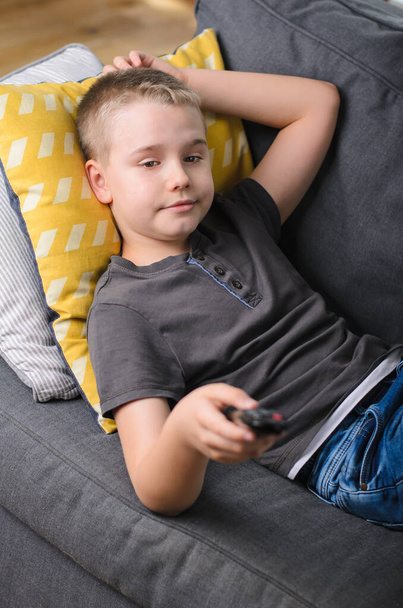 adolescent garçon étendu sur canapé regarder la télévision à la maison. Boy commute la télécommande. Concentration sélective
 - Photo, image