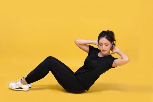 Smile happy Beautiful portrait young Asian woman stretching exercise workout on yellow background, fitness sport girl aerobic and healthy concept. - Fotó, kép