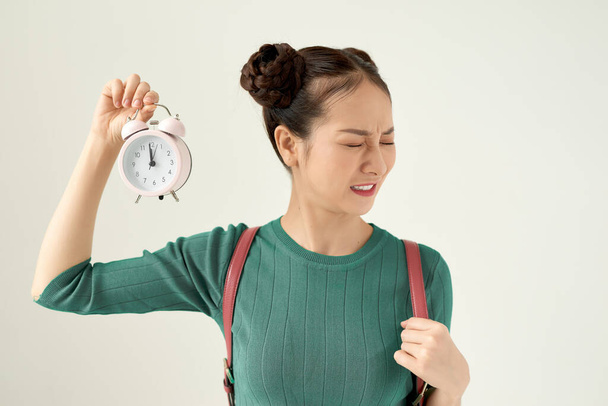 Young asian woman feeling confused and uncertain, doubting with puzzled look holding a clock - Foto, imagen
