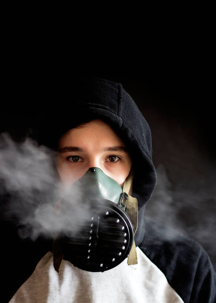 Teenager in a gas mask on a black background - Foto, afbeelding