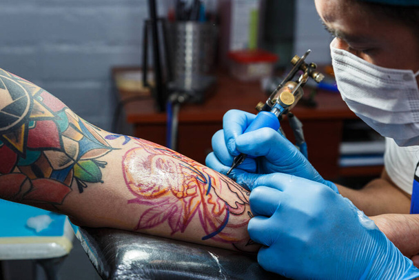 татуювання на машині татуювання на руці з дизайном намальованим та використанням захисної маски проти ковадла 19, концепція мистецтва та дизайну
 - Фото, зображення