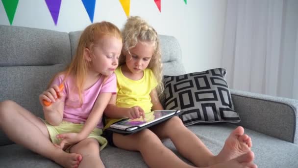 Zwei beste Freundinnen. Rotschopf mädchen essen karotte und blond ein mit tablette - Filmmaterial, Video