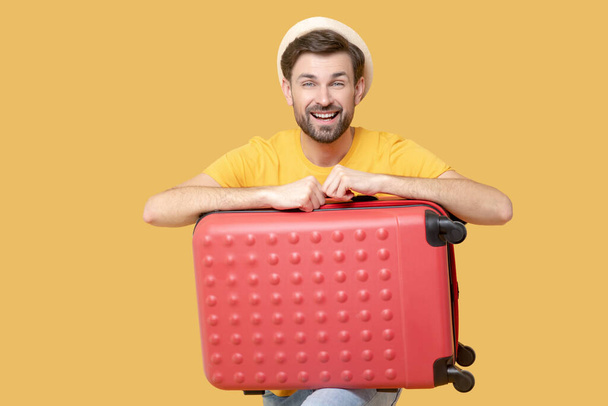 Smiling young adult man with a red suitcase - Fotoğraf, Görsel