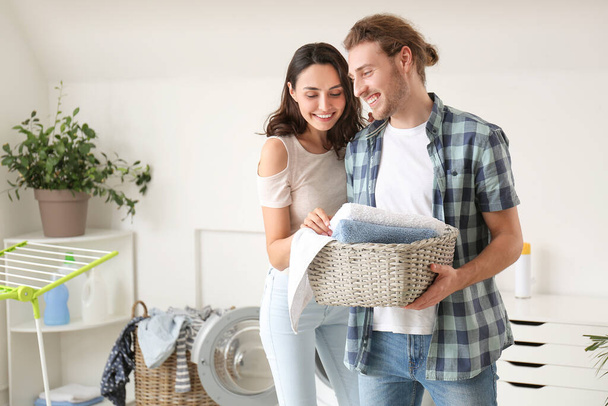 Happy young couple doing laundry at home - Фото, изображение