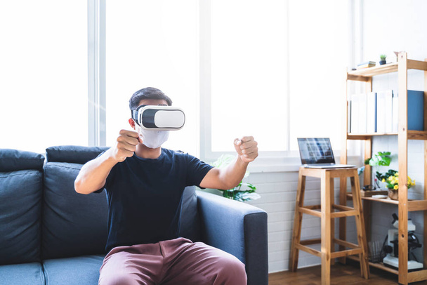 Virtual reality VR headset experience driving simulation, Asian man interacting in augmented reality playing game having fun, futuristic technology at home wearing facemask quarantine isolation  - Foto, Imagem
