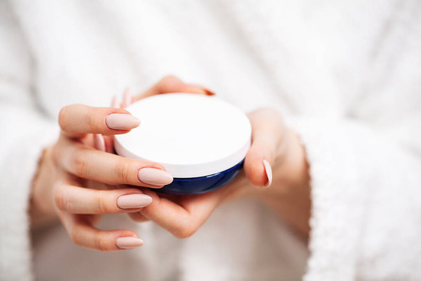 A woman uses a moisturizer to take care of her skin - Zdjęcie, obraz
