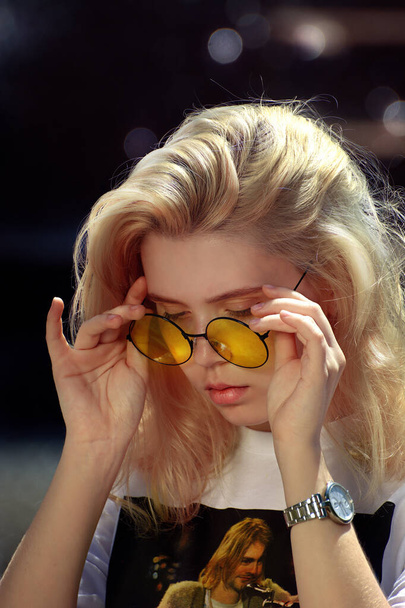 Rostov. Russia. 19.05.2019. City park.  Young blonde in yellow stylish round glasses. White t-shirt with a picture of Kurt Cobain. For editorial use only - Foto, immagini