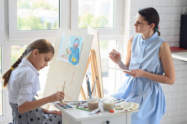 Mam en schoolbord zijn dol op schilderen en tekenen zittend bij het raam in een weekend - Foto, afbeelding