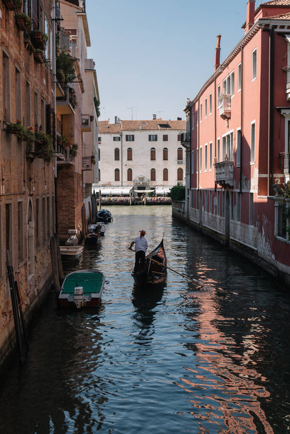 Venice, Italy - August 13, 2016: Gondolier drives a gondola with tourists on a canal in Venice, Italy. - Photo, image