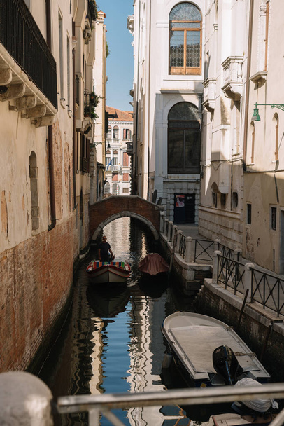 Venice, Italy - August 13, 2016: One man is riding a boat on a deserted canal of Venice, Italy. - 写真・画像