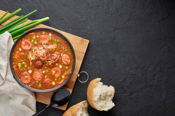 Куриный и колбасный суп гамбо в черной миске на темном фоне. Гумбо это суп из блюд каджун с руксом. Американская еда. Традиционная этническая еда. Копирование пространства
 - Фото, изображение