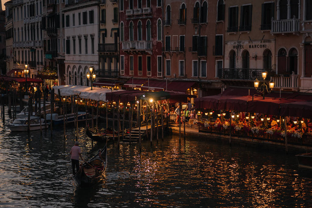 ヴェネツィア、イタリア- 2016年8月13日:イタリアのヴェネツィアでの夜の光の中で大運河の遊歩道のレストラン. - 写真・画像