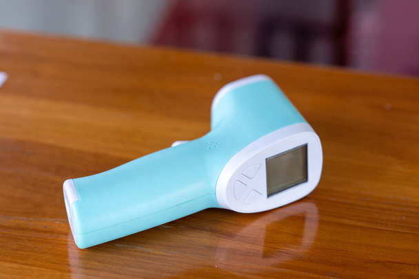 Infrarot-Thermometer isoliert auf hölzernem Hintergrund zur Messung der Körpertemperatur. - Foto, Bild