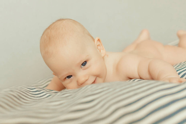 Adorable baby boy lying on his stomach and smiling. - Φωτογραφία, εικόνα