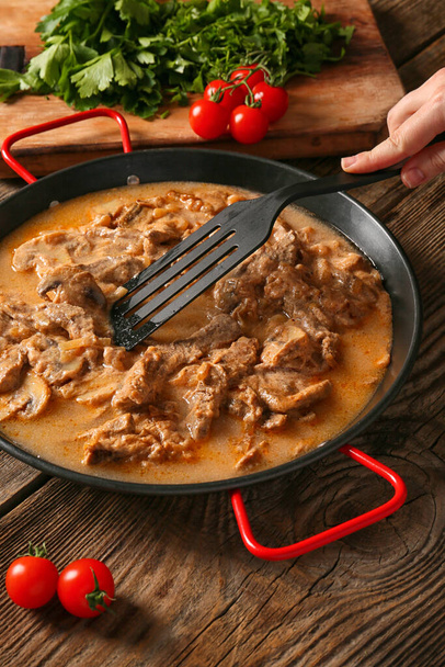 Woman cooking tasty beef stroganoff on table - Photo, Image