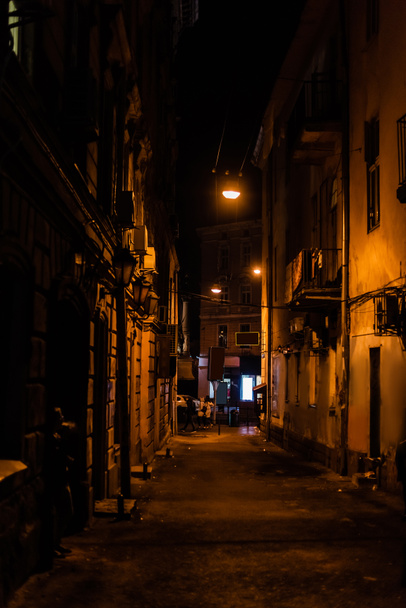 Menschen gehen auf dunklen Straßen mit alten Häusern  - Foto, Bild