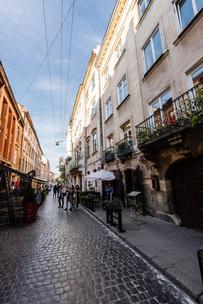 LVIV, UKRAINE - OCTOBER 23, 2019: street cafe and people walking along narrow street in city center - Foto, imagen