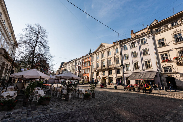 LVIV, UKRAINE - OCTOBER 23, 2019: people sitting in street cafe near old houses in city center - Photo, image