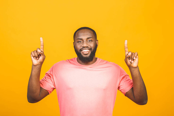 Πορτρέτο του χαρούμενου νέου όμορφη αφρο-Αμερικανός άνθρωπος με casual χαμόγελο, δείχνοντας κατά μέρος με το δάχτυλο, κοιτάζοντας στην κάμερα με συγκινημένη έκφραση προσώπου - Φωτογραφία, εικόνα