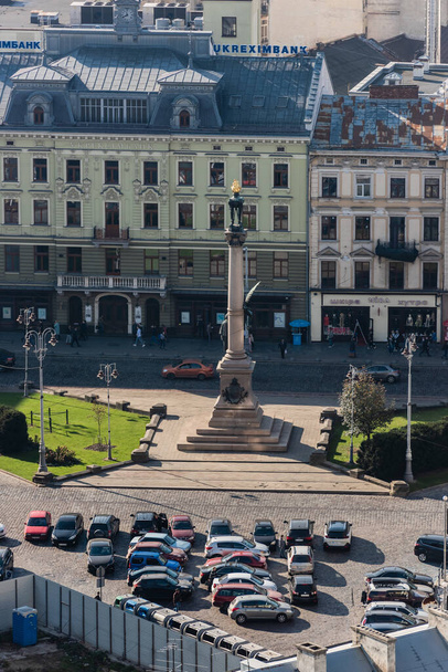 LVIV, UKRAINE - OCTOBER 23, 2019: aerial view of Adam Mickiewicz Monument near car parking and authentic houses  - 写真・画像