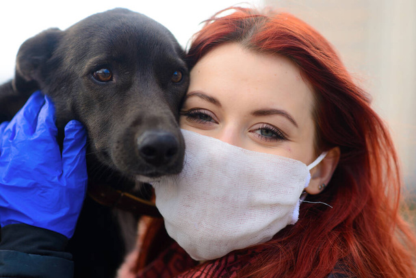 Młoda samica używająca maski jako koronawirusu rozprzestrzeniającego profilaktykę spaceru z psem. Światowa koncepcja pandemii COVID-19. - Zdjęcie, obraz
