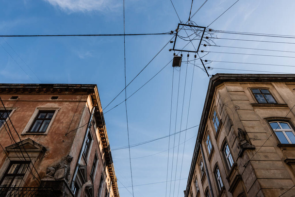low angle view of old buildings and electrical wires against blue sky in lviv, ukraine - Foto, Imagem
