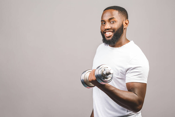 Fitness concept. Portrait of a happy african american black man with dumbbells isolated over grey background. - Foto, immagini