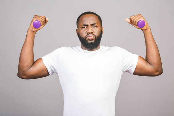 Fitness concept. Portrait of a happy african american black man with dumbbells isolated over grey background. - Photo, Image