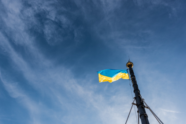προβολή χαμηλής γωνίας της ουκρανικής σημαίας σε κοντάρι σημαίας κατά του μπλε ουρανού στο lviv, ukraine - Φωτογραφία, εικόνα