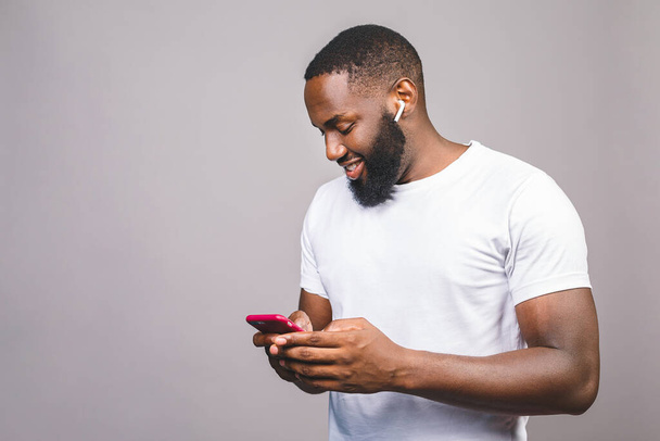 Portrait of handsome excited cheerful joyful delightful curious guy wearing casual sending and getting messages to his lover isolated against grey background. Using phone. - Photo, Image