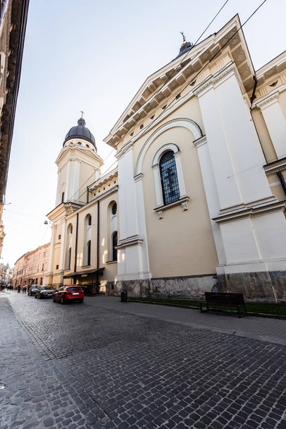 LVIV, UKRAINE - OCTOBER 23, 2019: carmelite monastery wall and church, and cars parked on street - Zdjęcie, obraz