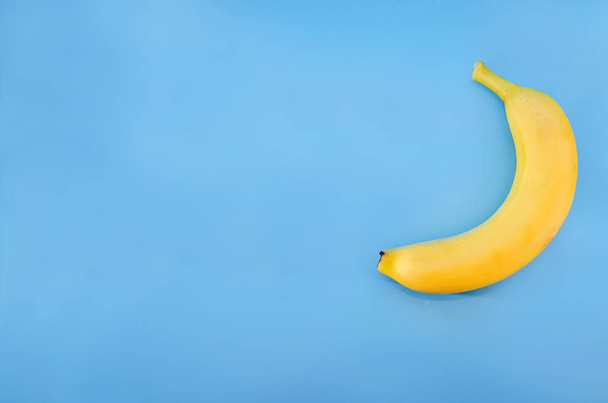 yellow banana isolated on a blue background. Copy space. Place for the test. - Valokuva, kuva