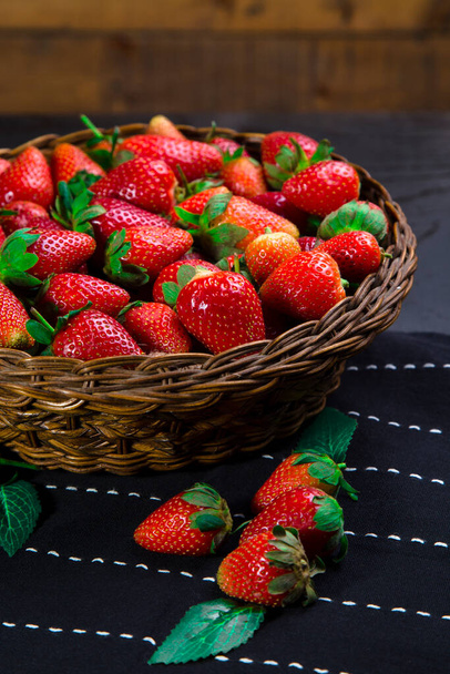 Juicy strawberries arranged in rattan bowl on table runner - Foto, afbeelding