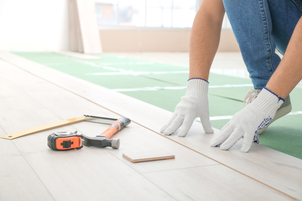Carpenter installing laminate flooring in room - Photo, Image