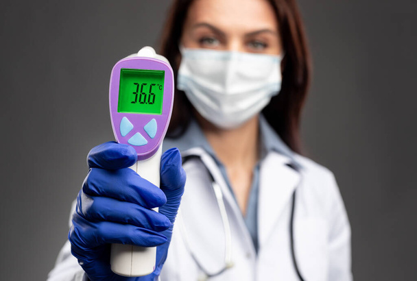 Nurse showing infrared thermometer with normal temperature - Valokuva, kuva