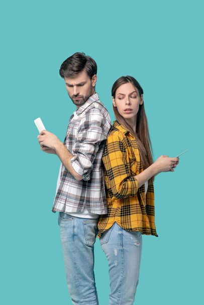 Man and girl in checkered shirts with smartphones. - 写真・画像