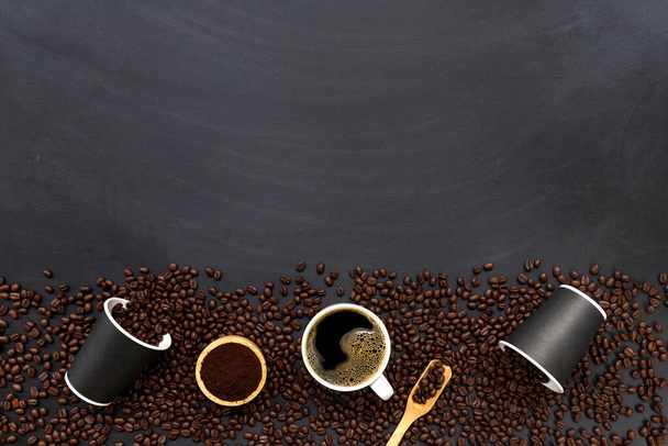 kopje koffie en bonen op zwarte houten tafelondergrond. bovenaanzicht - Foto, afbeelding