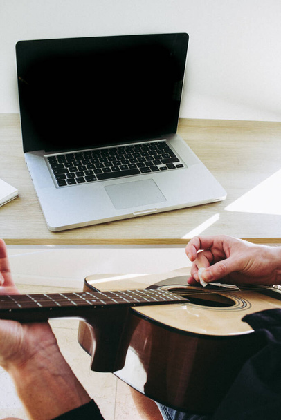 man leren gitaar spelen online met behulp van laptop - Foto, afbeelding
